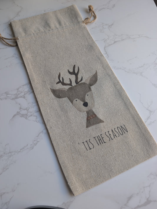 Textile bag with deer design and 'Tis the Season text on a marble surface