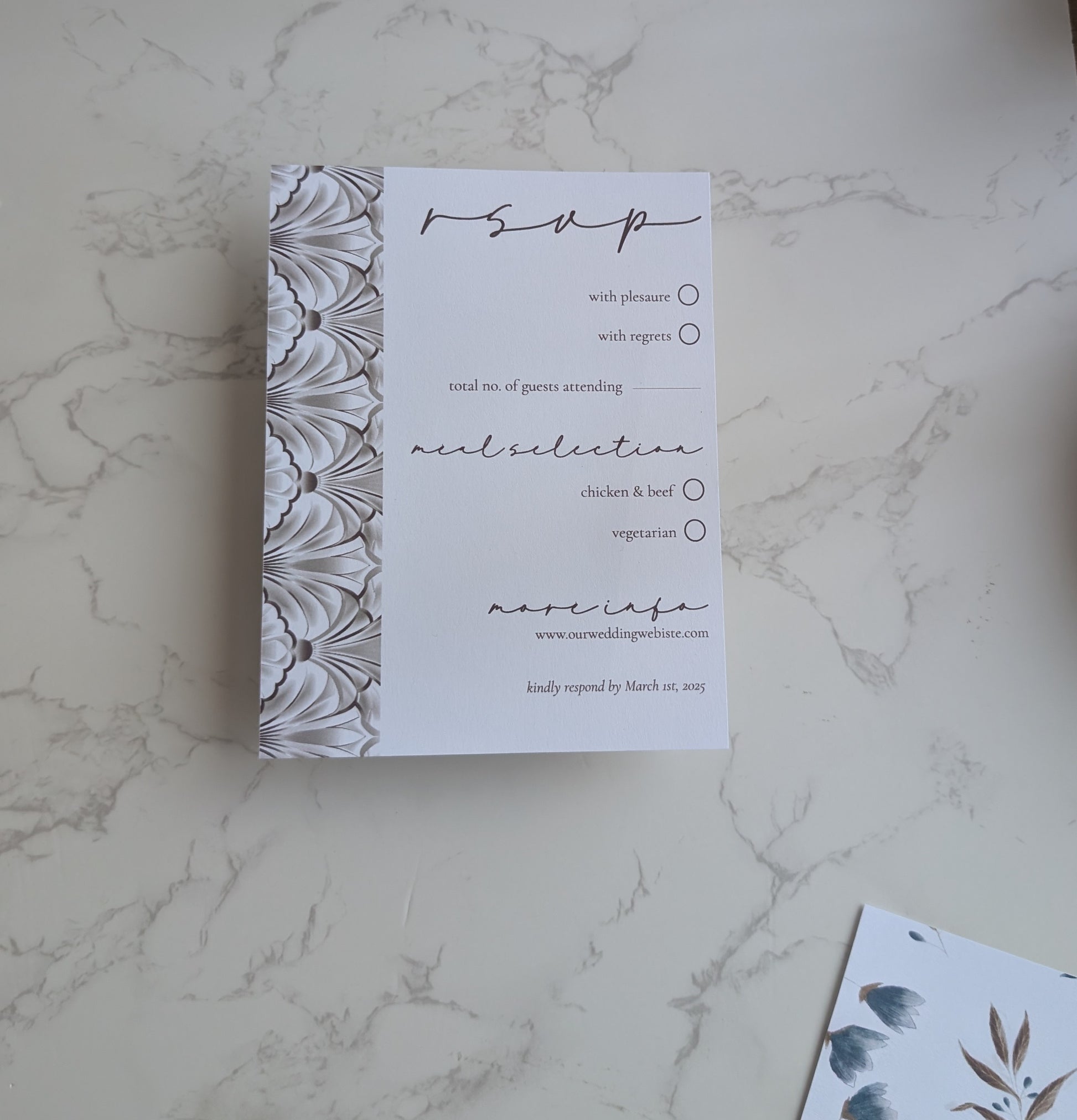 RSVP card with decorative border on a marble surface