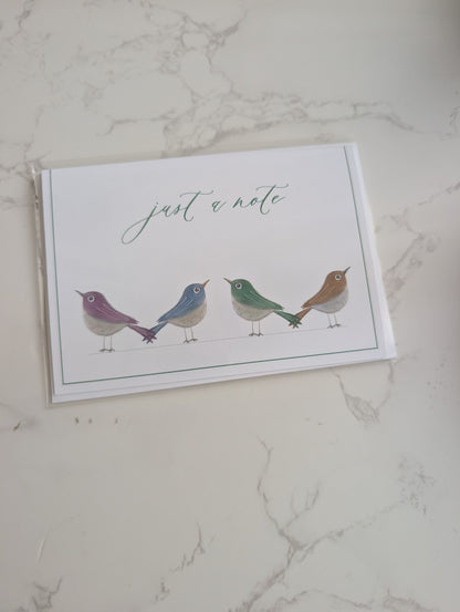 Note card with birds illustration and 'just a note' text on a marble surface