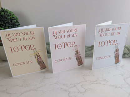 Three baby shower cards with a bottle design on a marble surface.