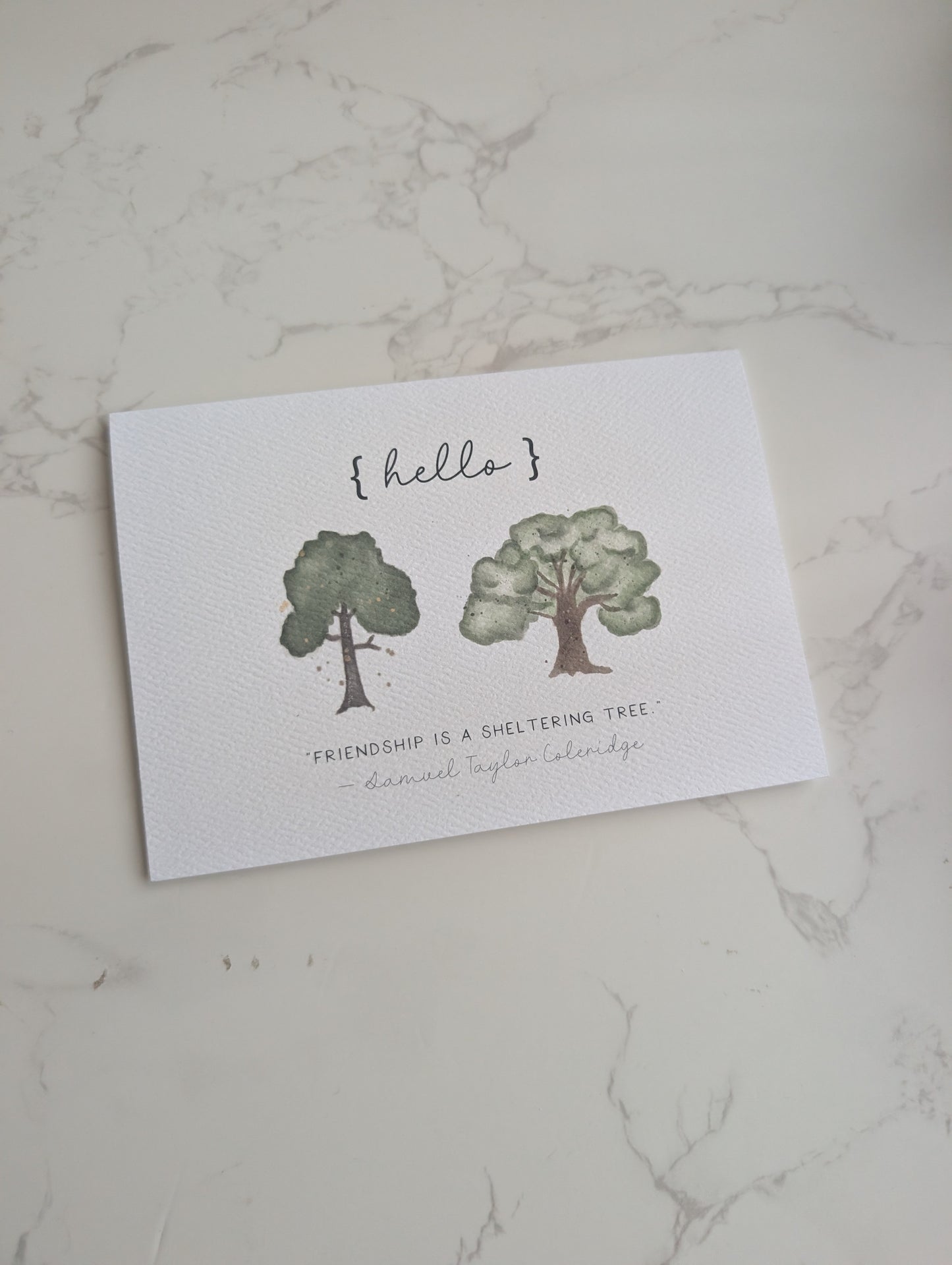 Greeting card with tree illustrations and text on a marble surface