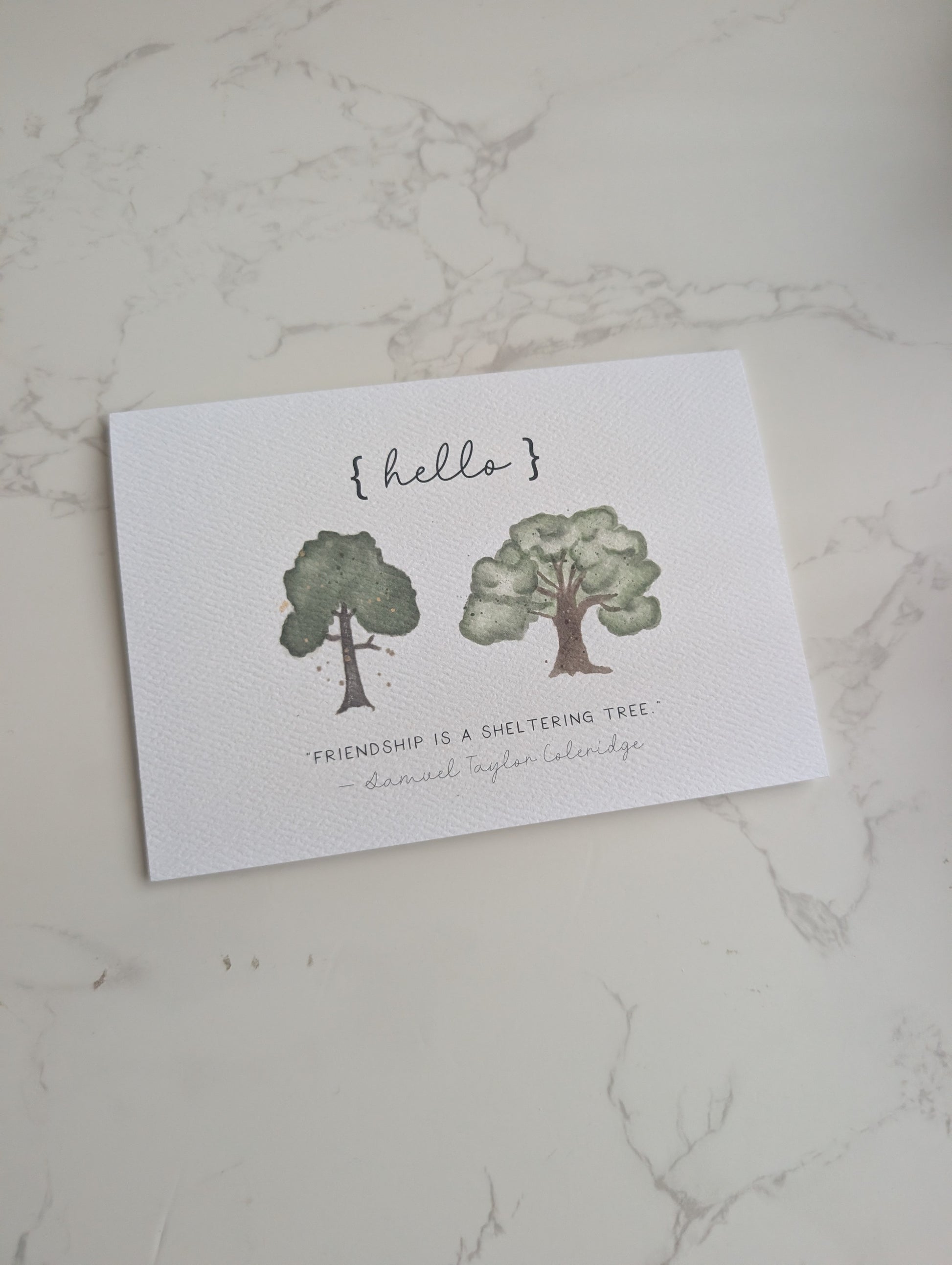 Greeting card with tree illustrations and text on a marble surface
