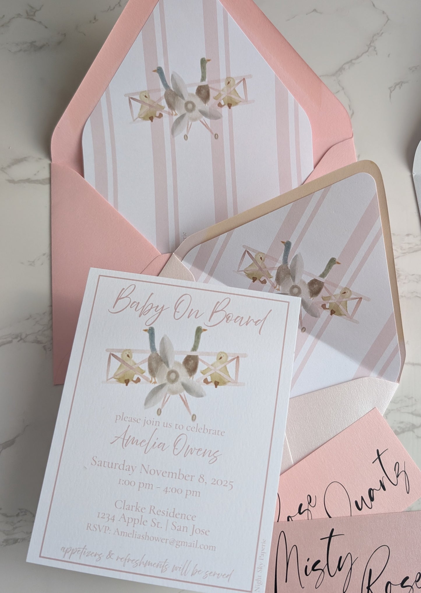 Baby shower invitation with pink envelope on a marble surface