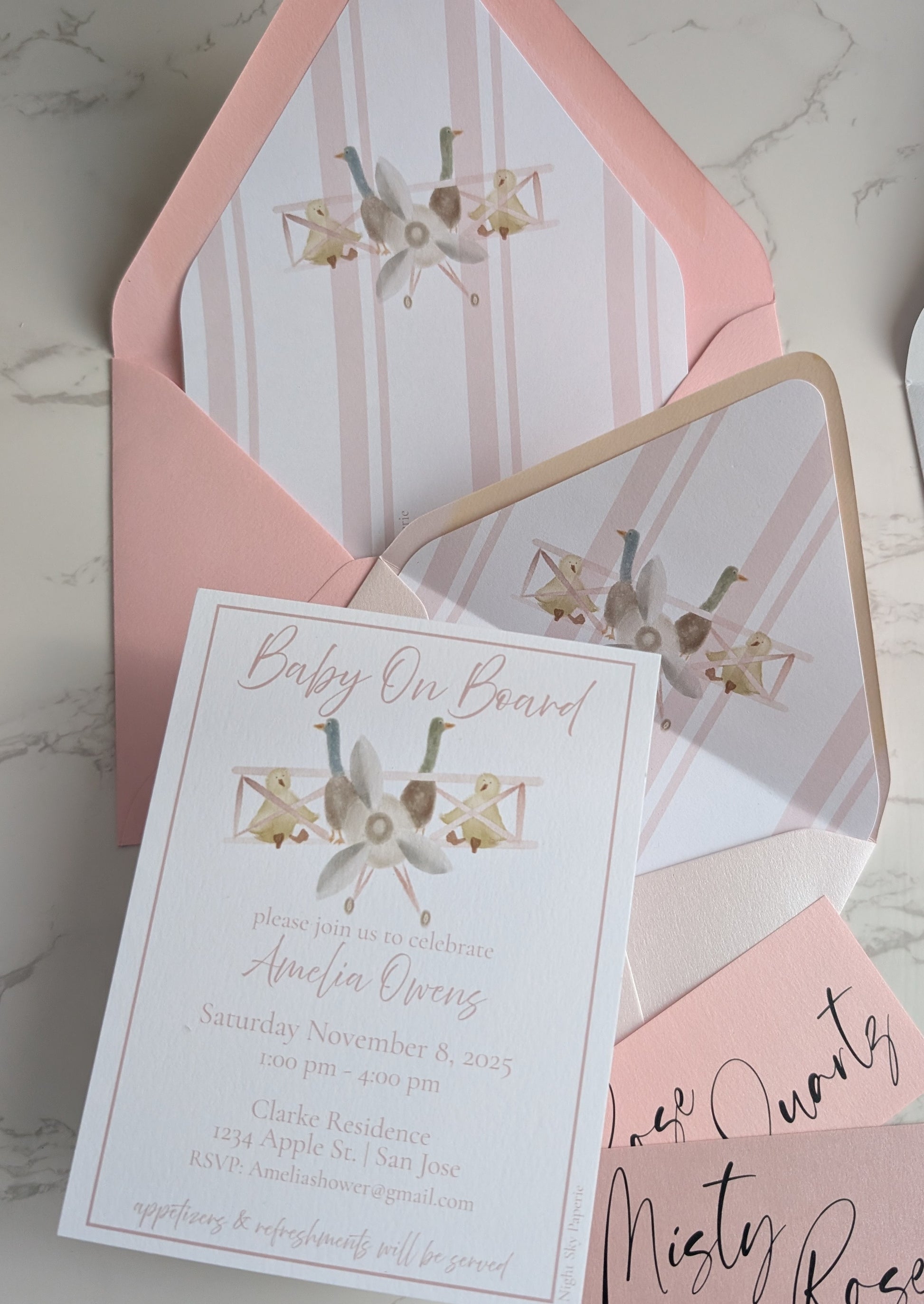 Baby shower invitation with pink envelope on a marble surface
