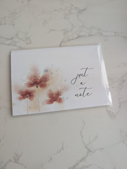 Note card with floral design and 'just a note' text on a marble surface