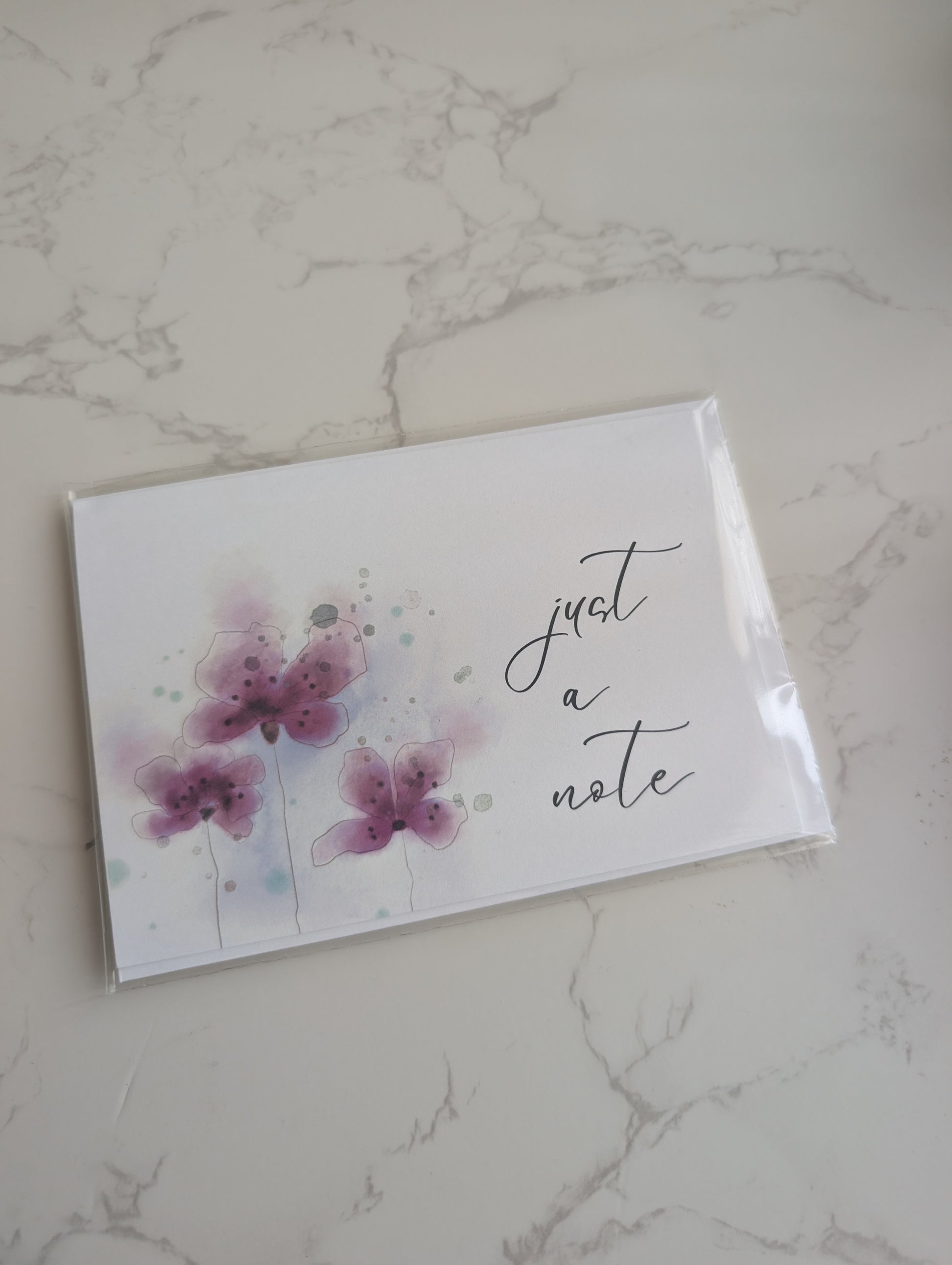 Note card with floral design and 'just a note' text on a marble surface
