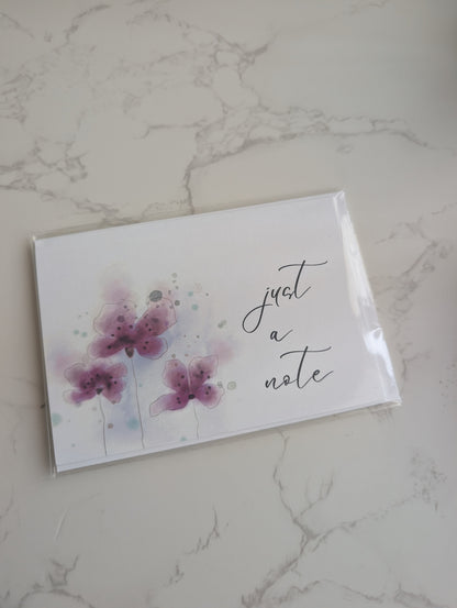 Note card with floral design and 'just a note' text on a marble surface